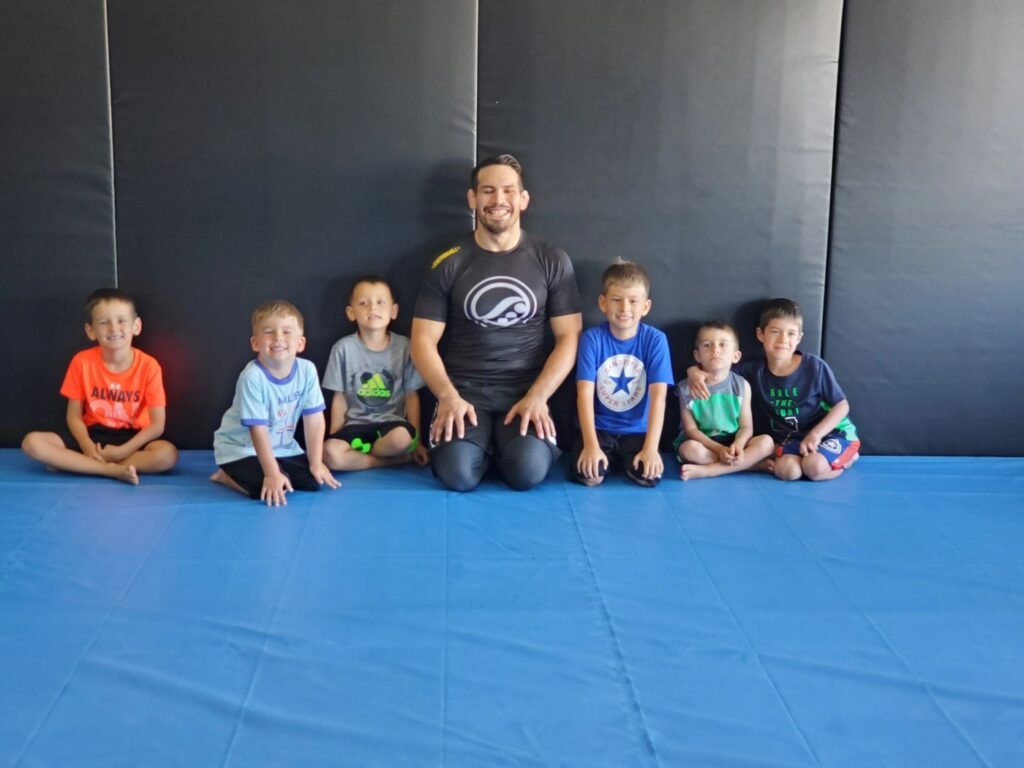 Kids jiu jitsu students with their coach